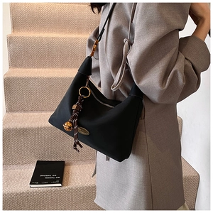 Détail du sac demi-lune noir mat avec breloque faite main et bandoulière en cuir