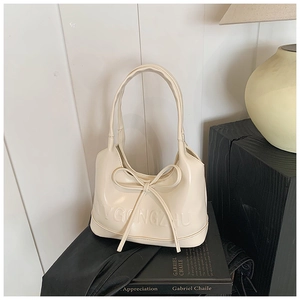 Gros plan du sac bandoulière blanc crème avec nœud 3D et gaufrage logo élégant