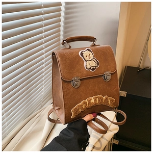Detailed close-up of brown vintage PU backpack with silver buckles and cartoon bear patch