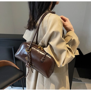Detail of vintage brown shoulder bag with shiny leather texture and gold metal charms