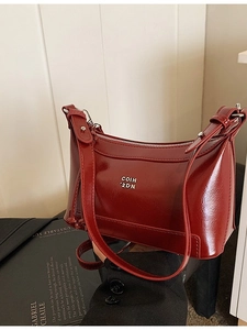 Deep red glossy leather pillow bag with silver metal logo and adjustable shoulder strap