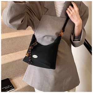Détail du sac bandoulière noir avec plaque en métal handmade et pendentif cloche doré