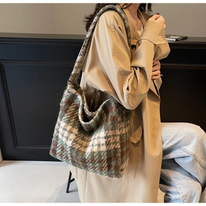 Klassieke geruite tote bag van dikke wol gedragen op de schouder van een model