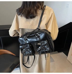 Detail view of black glossy PU leather backpack with white stitching and bow pockets