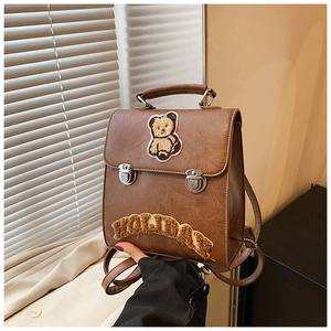 Detail of brown vintage backpack with teddy bear patch and HOLIDAY embroidery text