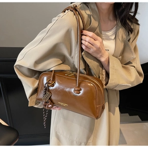 Close-up of brown vintage patent leather shoulder bag with gold zipper and woven detail