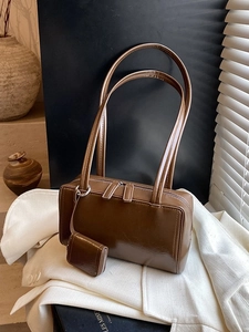 Deep brown glossy faux leather boston bag with mini pouch on white blazer background
