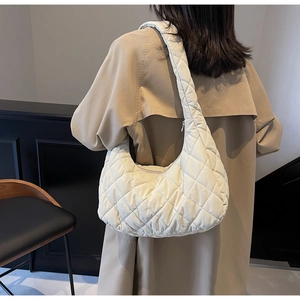Close-up of quilted cream hobo bag showing padded texture and seamless shoulder strap