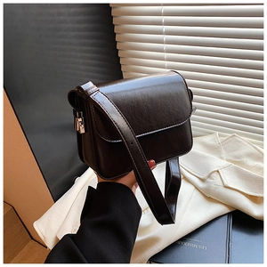Close-up of a deep brown shiny PU leather square bag with a silver metal clasp