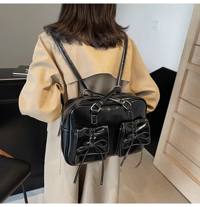 Detail of a black glossy leather backpack with bow-knot pockets and white contrast stitching