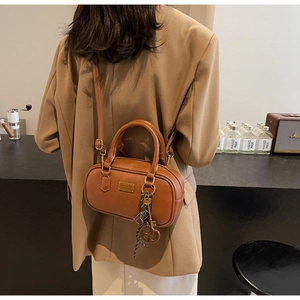 Detailansicht einer braunen Leder-Bowling-Tasche mit Goldbuckle und gewebtem Anhänger-Detail