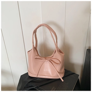 Détail d'un sac cabas rose clair avec un grand nœud décoratif et une texture en similicuir