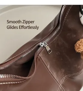 Détail du zip argenté fluide et des surpiqûres blanches sur le sac fourre-tout marron