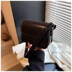Detailed view of dark chocolate brown leather square bag with flap closure and strap