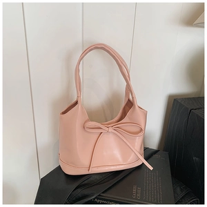Détail du sac sous l'aisselle rose avec un grand nœud décoratif et une texture lisse