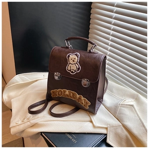 Detail of vintage brown backpack with cute bear embroidery and fuzzy letter patch