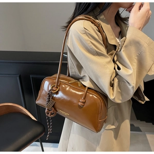 Retro caramel leather bowling bag detail showing side view on model with trench coat