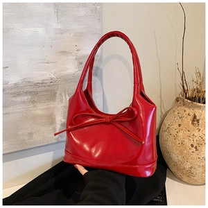 Vue détaillée du sac porté épaule en cuir verni rouge avec nœud et poignée arrondie