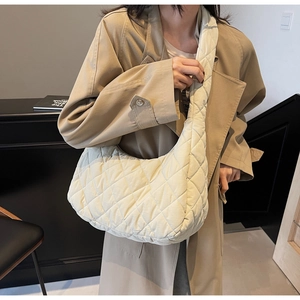 Detailed view of beige quilted crossbody puffer bag with padded rhombic pattern texture