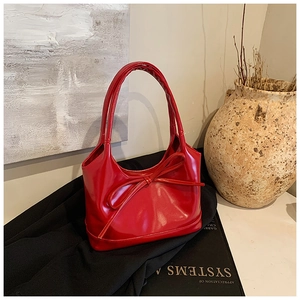 Vue détaillée du sac à main en cuir verni rouge avec nœud et décor vintage artistique