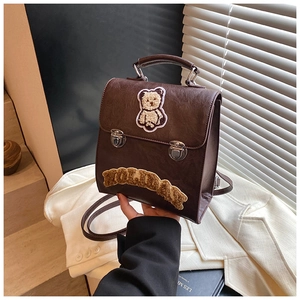 Detail of vintage brown backpack with cute bear embroidery and metal lock closure