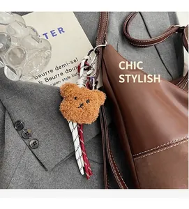 Détail d'un mignon ours en peluche marron avec cordon tressé sur un sac en cuir chic