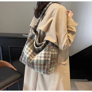 Detail van vintage geruite shopper in bosgroen en bruin op model met een trenchcoat aan