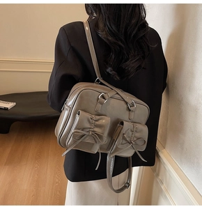 Detail of taupe patent leather tote featuring dual front pockets and bow accents