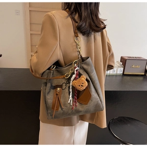 Detail view of large contrast tote bag with teddy bear charm and metal chain strap