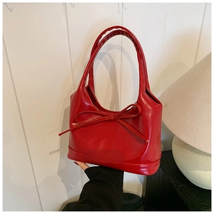 Détail d'un sac à bandoulière rouge brillant en similicuir avec un nœud décoratif fin