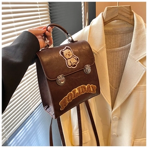 Detail of dark brown leather backpack with teddy bear patch and holiday embroidery