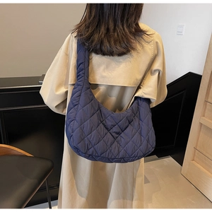 Detailed view of dark blue quilted crescent shoulder bag with elegant rhombic stitching