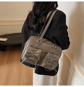 Detail of khaki leather tote bag with bow-knot pockets and glossy PU finish on model