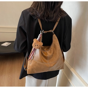 Gros plan du sac cabas vintage marron avec surpiqûres blanches et charme d'ours en peluche
