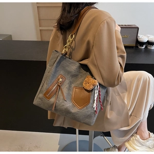 Detail of grey canvas tote bag with brown leather pockets and a cute bear charm