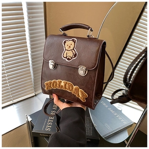 Detail of dark brown vintage PU leather backpack with plush bear and HOLIDAY embroidery