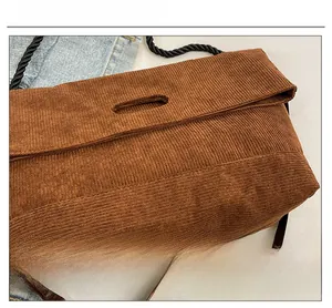 Detail of brown corduroy tote bag featuring an oval handle and dual strap textures