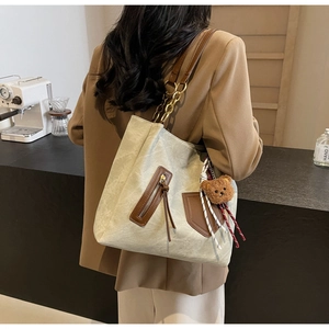 Close-up of contrast large tote bag with leather chain strap and cute bear charm
