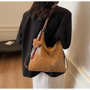 Détail du sac hobo marron caramel avec surpiqûres blanches et pendentif d'ours