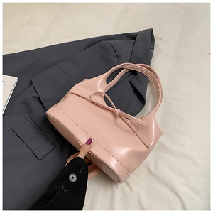 Vue détaillée du sac à main rose en cuir PU avec nœud sur fond de blazer gris foncé