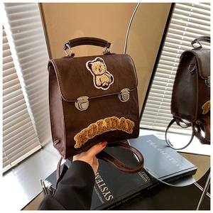 Close-up of retro brown faux leather backpack with plush bear embroidery and metallic buckles