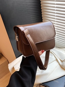 Retro brown leather crossbody bag with flap closure shown in a moody studio setting
