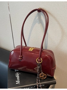 Deep red patent leather bowling shoulder bag with gold zippers and long top handles
