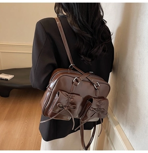Detail of dark brown glossy leather backpack with bow pockets and silver zippers