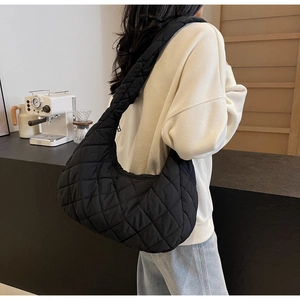 Detail view of black quilted puffer bag with large capacity and crescent silhouette