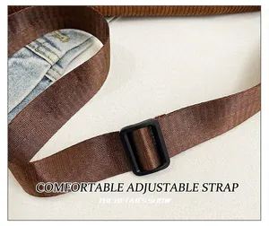Detail of a brown woven adjustable shoulder strap with a black matte rectangular buckle