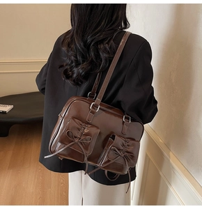 Detail of deep brown glossy patent leather tote with chic bow ties and front pockets