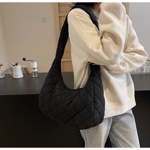 Detail of black quilted shoulder bag featuring premium padded texture and wide strap