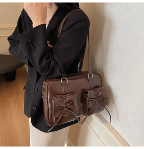 Detail of vintage dark brown tote bag showing dual bow-tie pockets and glossy texture