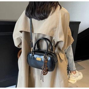 Detail einer schwarzen Boston-Tasche aus Leder mit goldenen Elementen zum Trenchcoat
